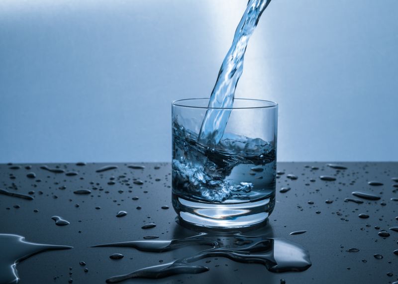 Botella de agua fría con rodajas de limón en mesa exterior
